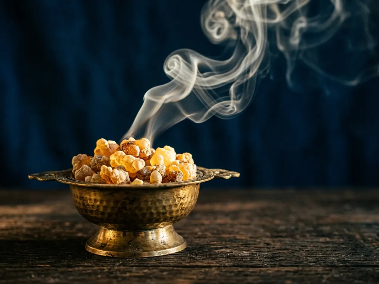 Incense smoke curling over loose resin and a brass censer
